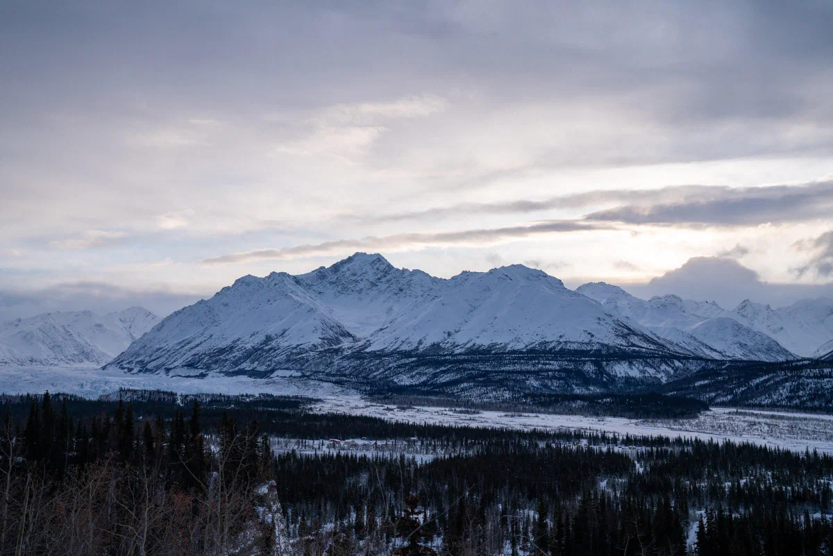 A broad snowy mountain range beneath an overcast sky.