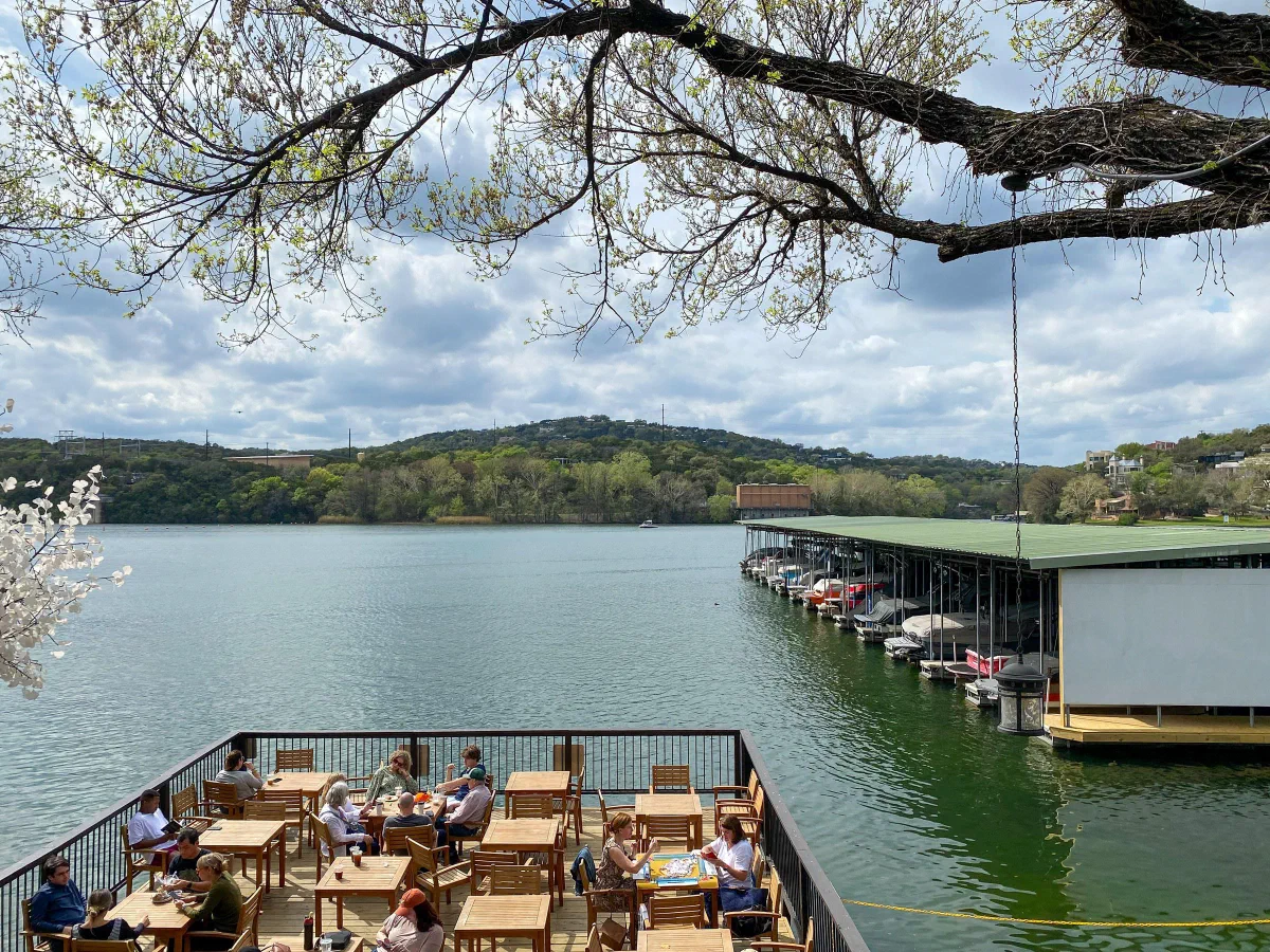An outdoor dining terrace and covered docks beside a lake.