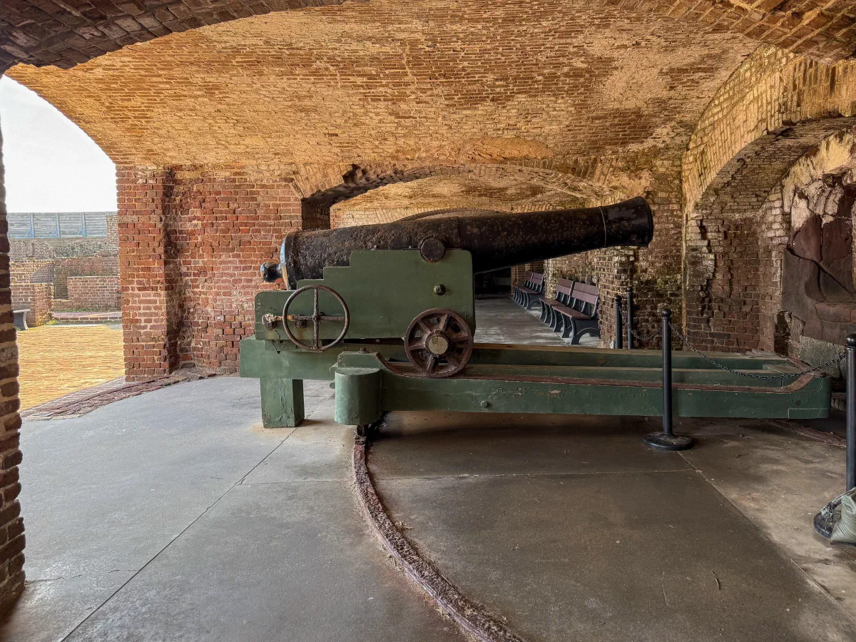 A historic cannon mounted inside an arched brick chamber.