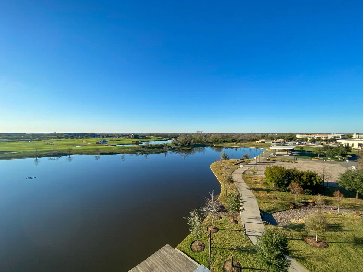 A lake and curving shoreline paths seen from above beneath a clear blue sky.