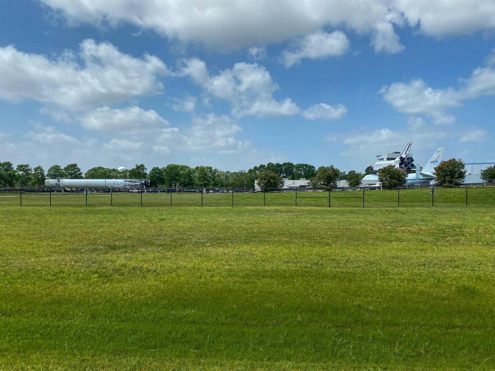 A broad green lawn beneath white clouds, with rocket displays in the distance.