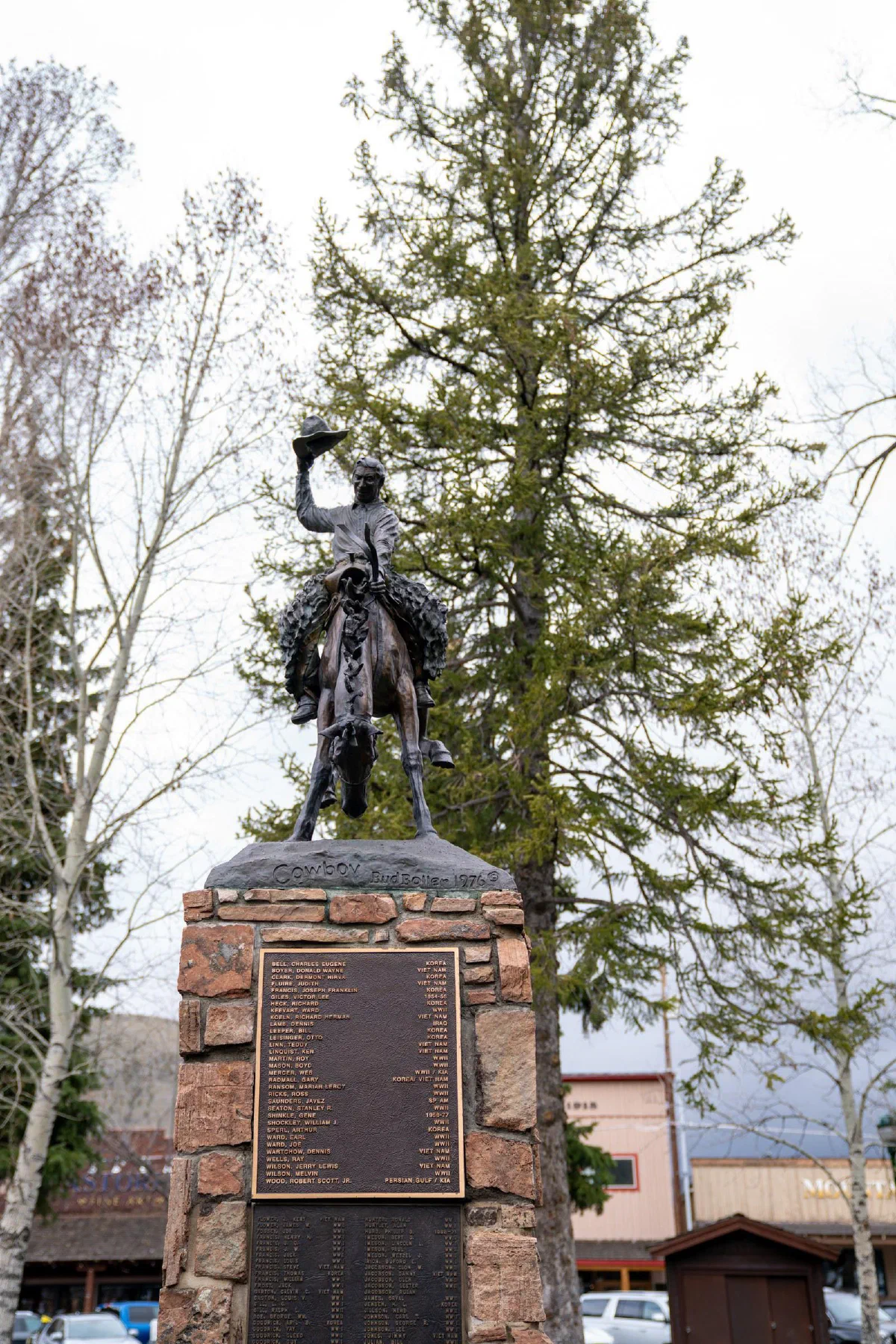 A bronze rider on horseback mounted on a stone memorial pedestal.