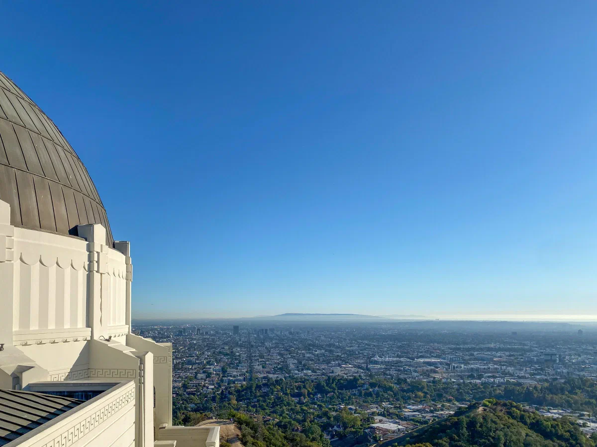 The curved wall and dome of an observatory above a broad city panorama.