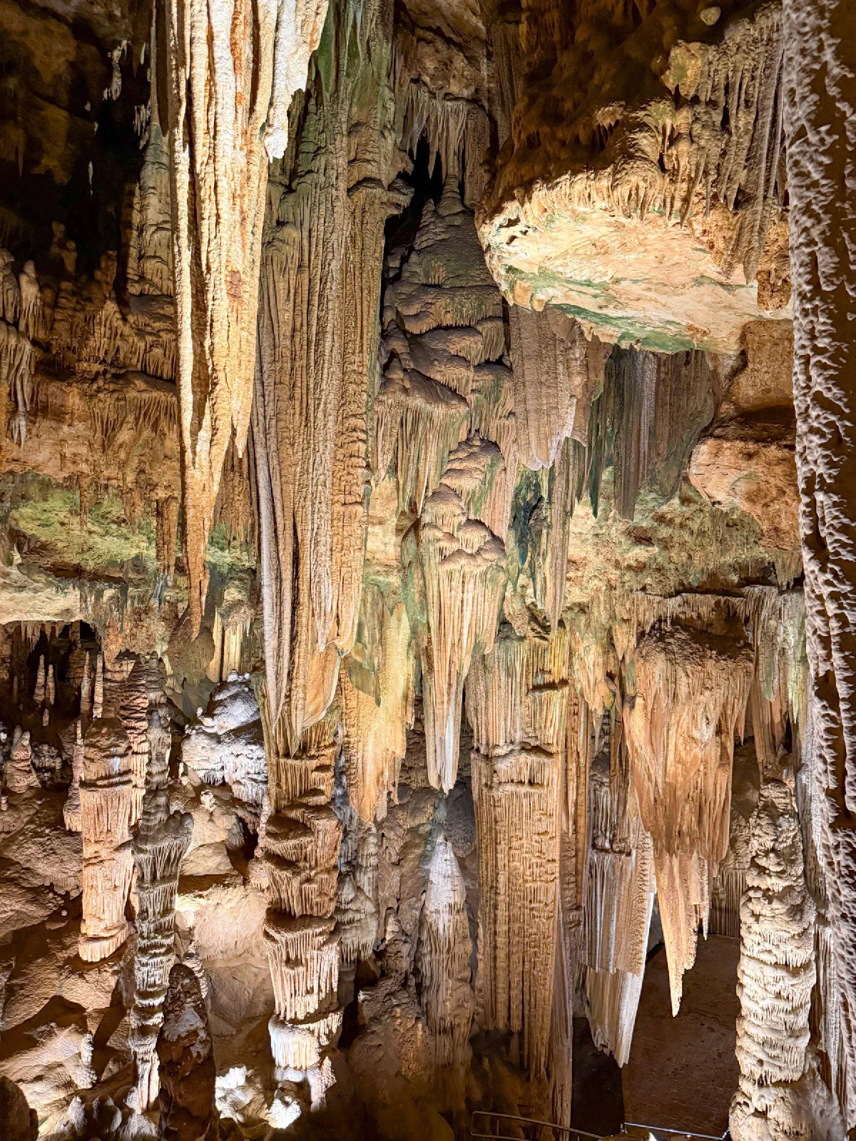 Long mineral formations hanging inside a cavern above smaller rock columns.