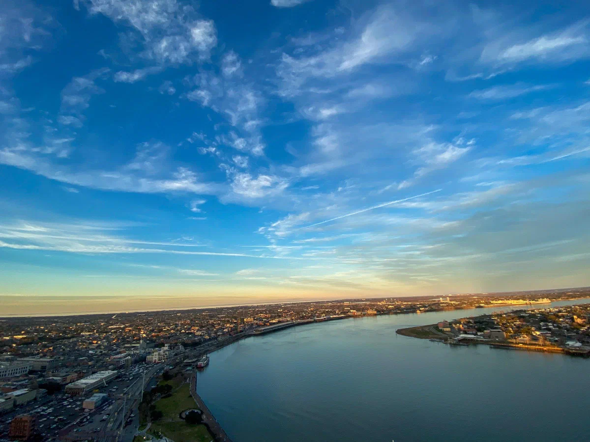 A broad river curving through the city beneath a blue sky streaked with clouds.