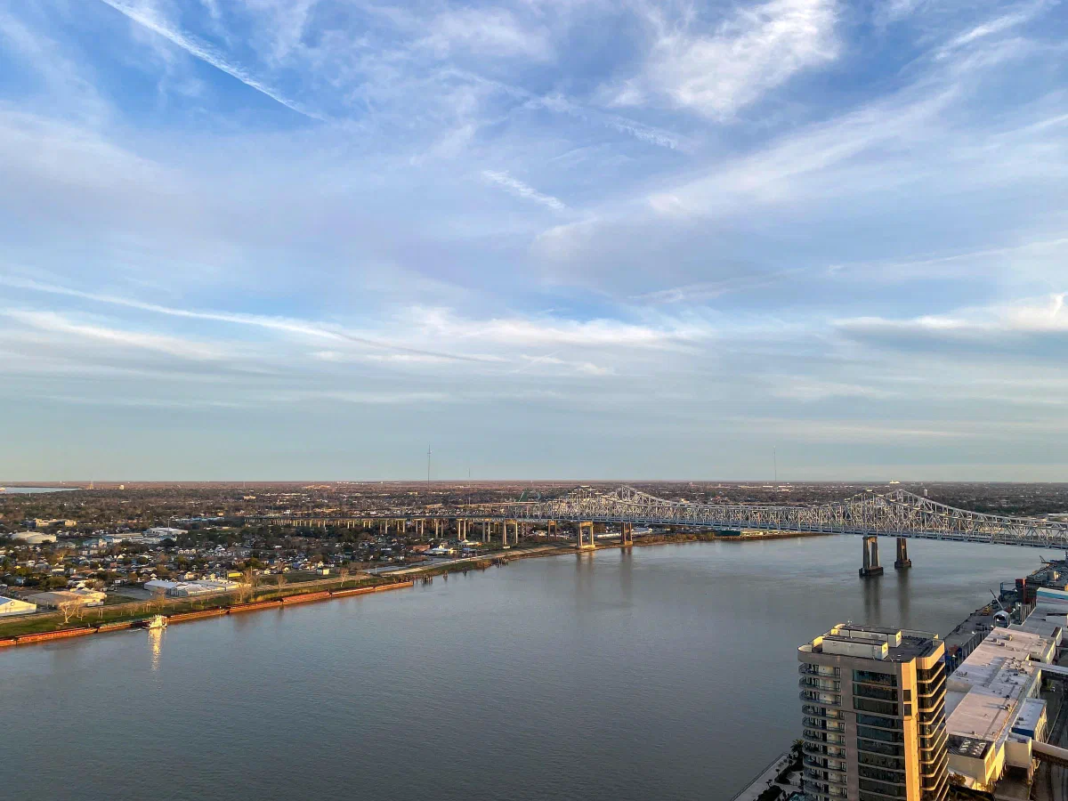 A wide river and bridges seen from above beneath a blue sky with wispy clouds.