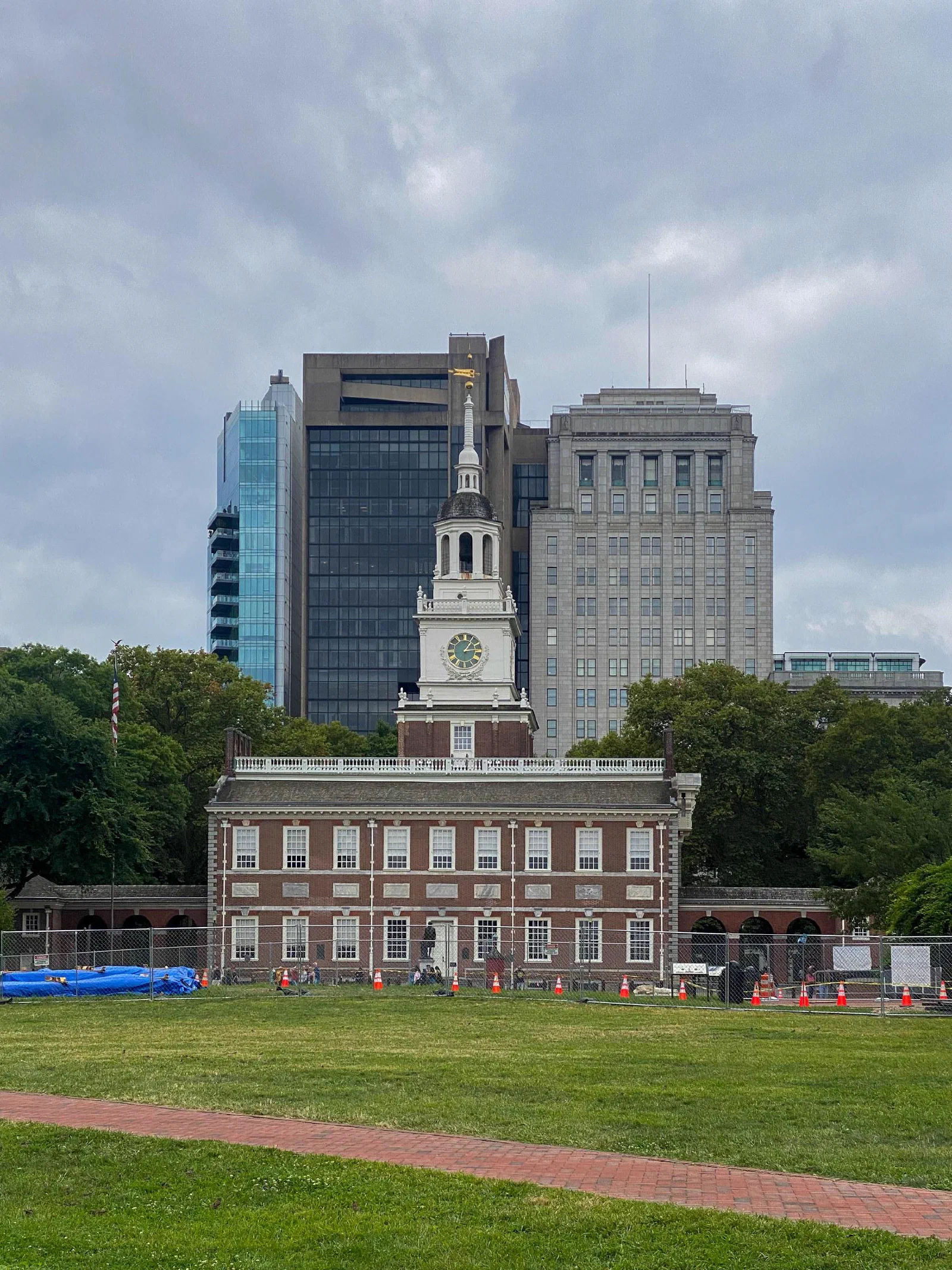 A red brick building with a white clock tower, a broad lawn, and taller buildings behind it.