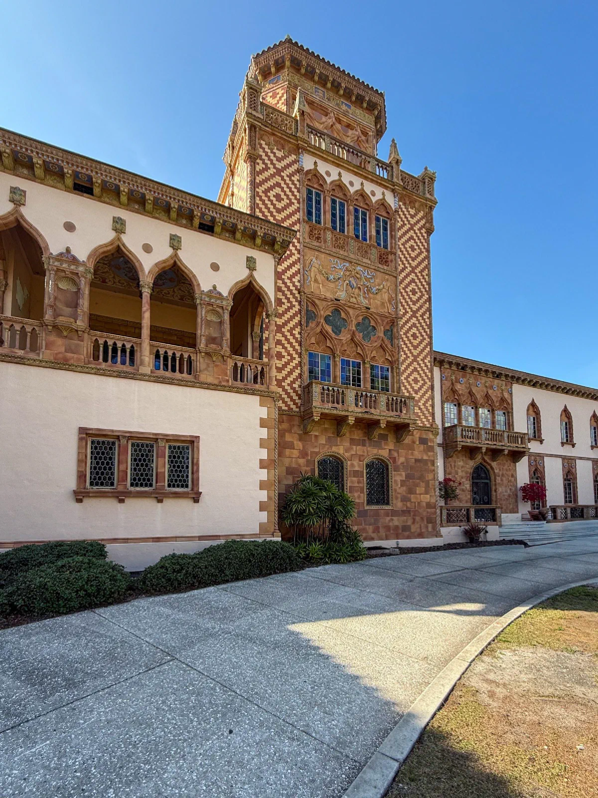 An ornate building with patterned stonework, arched balconies, and a square tower.