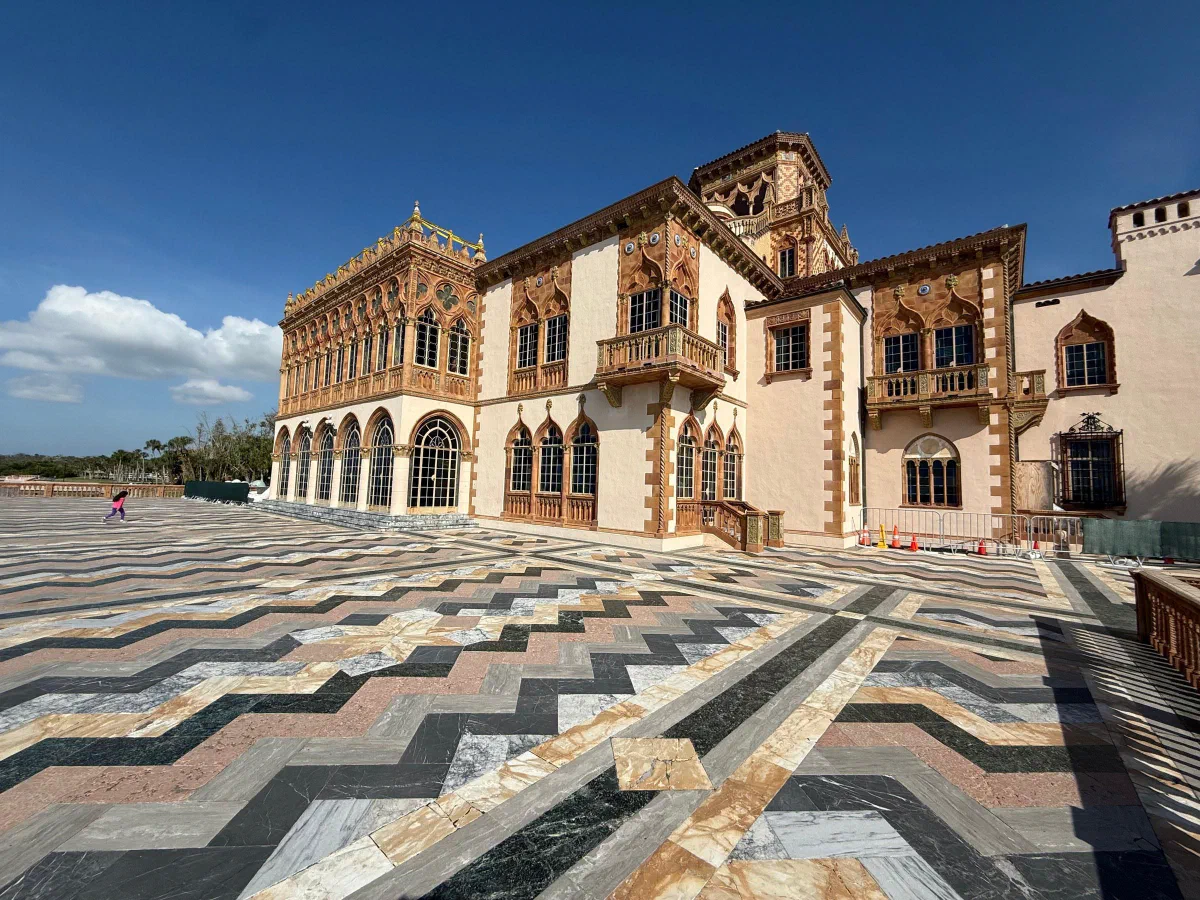 A richly decorated waterfront building beyond a terrace of patterned stone tiles.