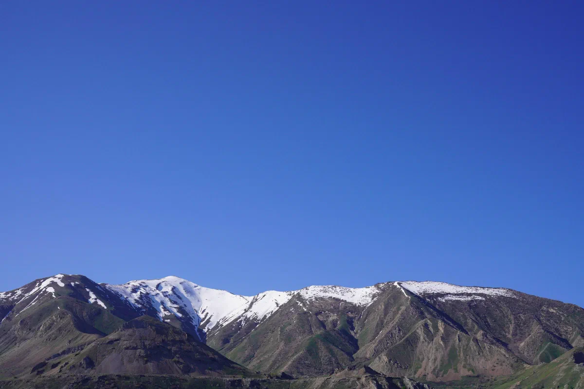 Snow-streaked mountain ridges beneath a wide, clear blue sky.