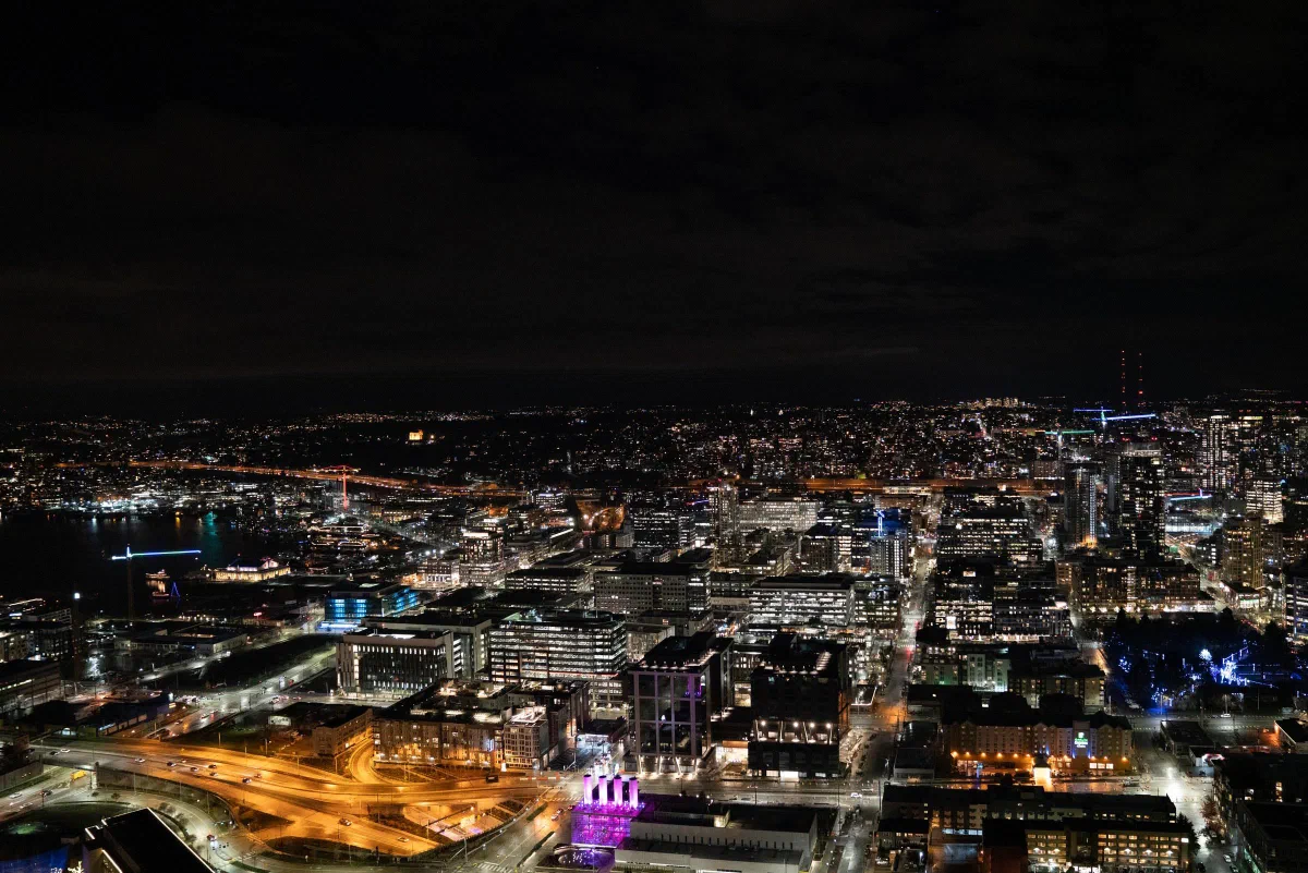 City buildings and roads illuminated at night, viewed from above.