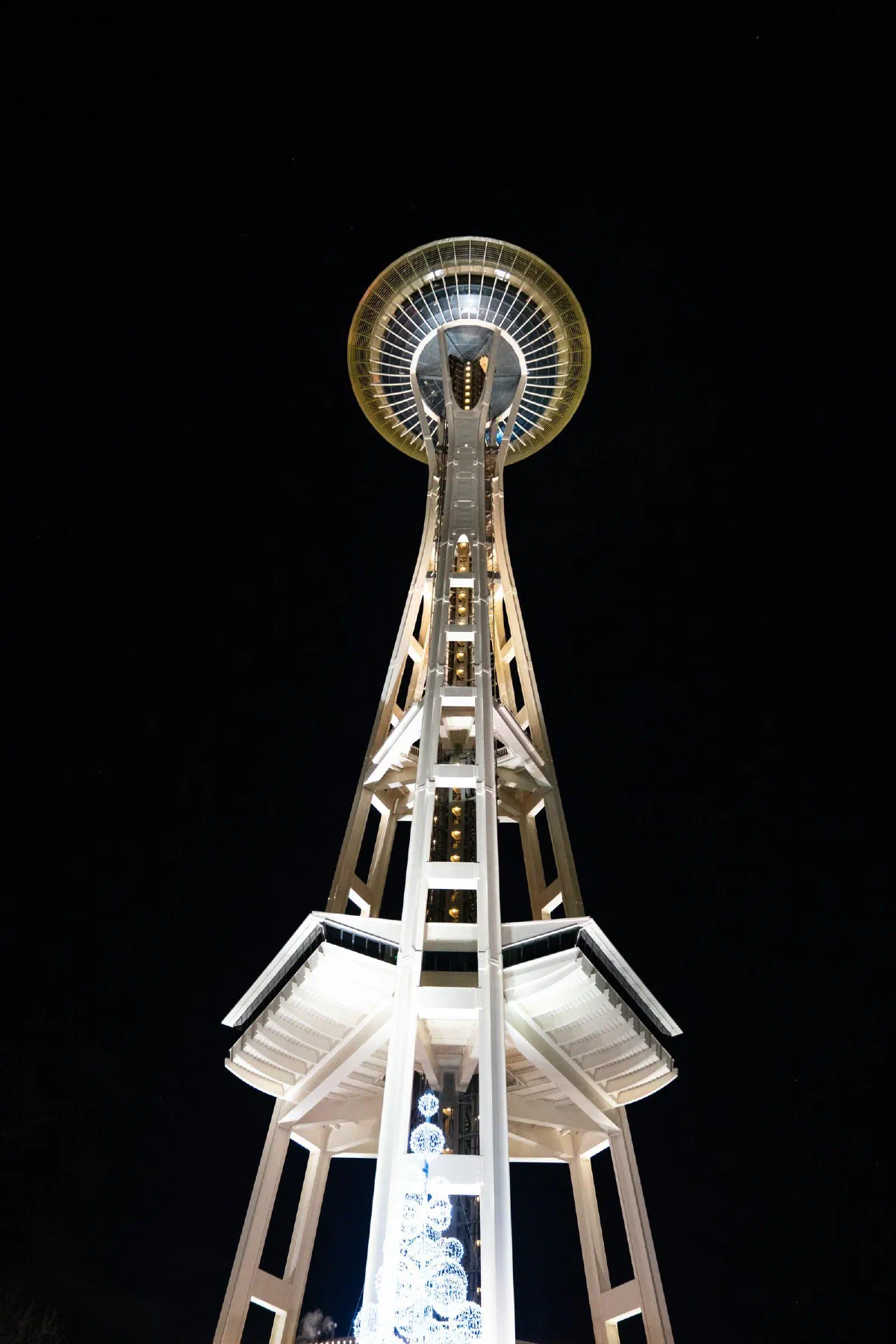 The Space Needle illuminated against a black night sky, viewed from below.