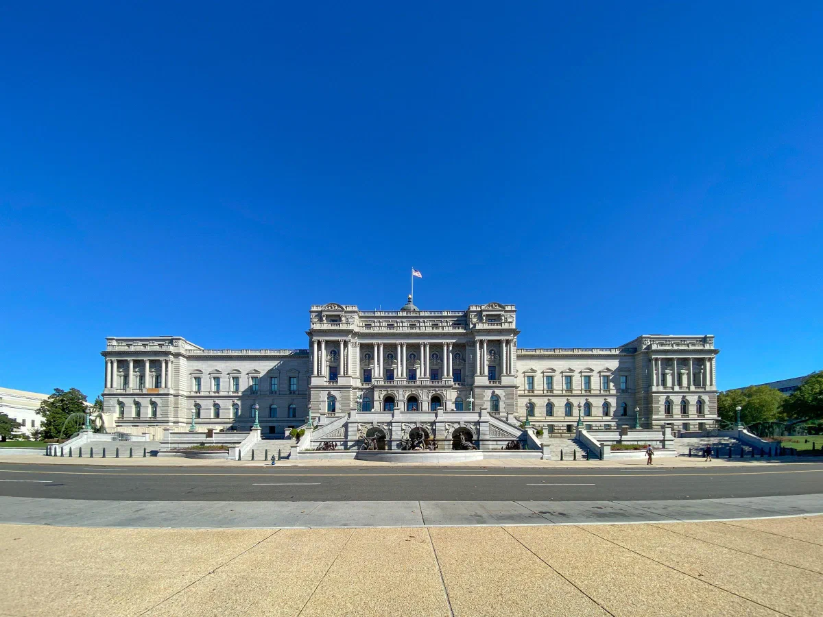 A pale stone building with columns and broad entrance steps beneath a clear blue sky.