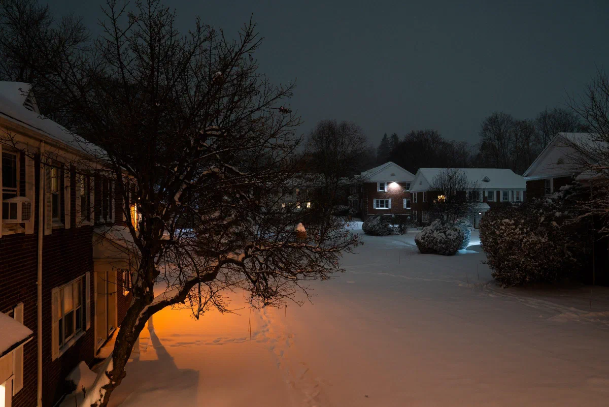 A snow-covered courtyard lit by a warm streetlight at night.