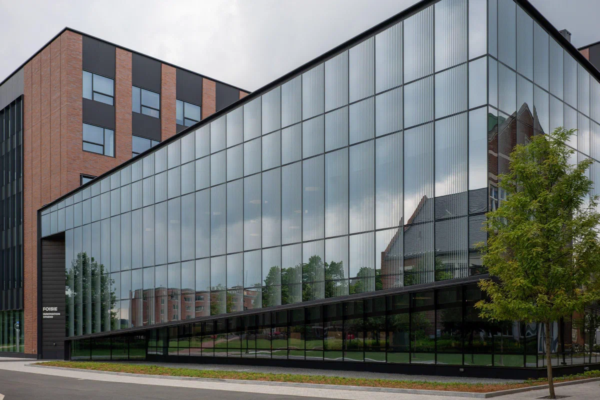 A modern building with a broad glass facade beside a paved path.
